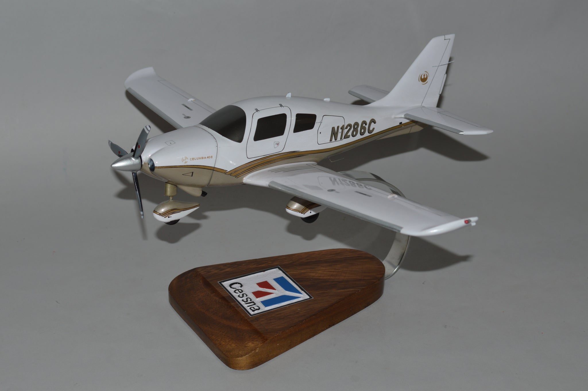 Model airplane on a wooden display base with a visible brand logo against a gray background