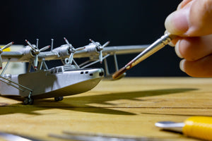 person painting a military airplane model